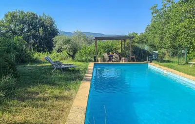 a blue swimming pool with a bench and a gazebo at Maison Avec Piscine in La Tour-dʼAigues