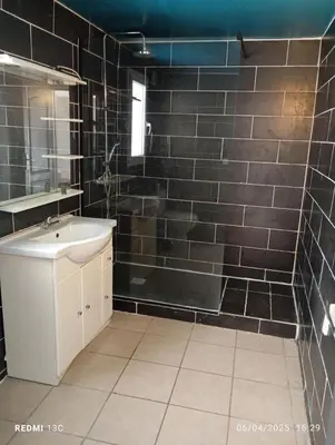 a bathroom with a sink and a shower with black tiles at Maison Provence Noe in Mallemort