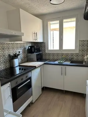 a kitchen with white cabinets and a stove top oven at Cocon douillet près du Cours Sextius in Aix-en-Provence
