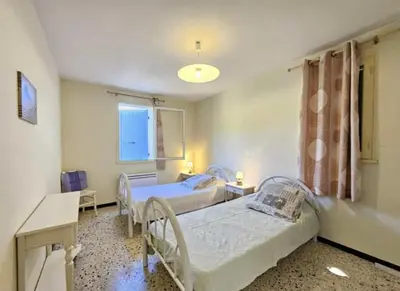 a bedroom with two beds and a window at La maison de Raffi in La Tour-dʼAigues