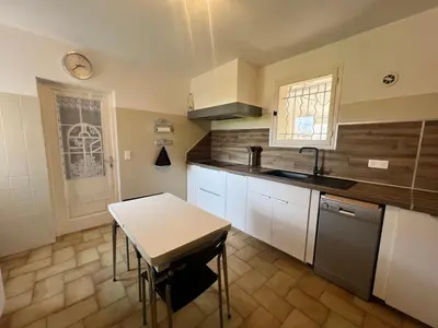 a kitchen with white cabinets and a table and a sink at La maison de Raffi in La Tour-dʼAigues