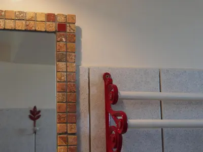a red towel rack on a wall next to a mirror at Une Heure Bleue in Manosque