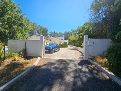 a house with a gate and a car parked in a driveway at Villa sous les pins in Ventabren