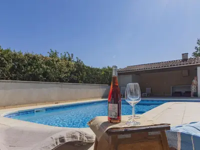 a bottle of wine and a glass next to a swimming pool at Villa A l'Ombre du Soleil by Interhome in Monteux
