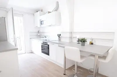 a white kitchen with a table and white appliances at T2 Centre historique d'Aix-en-Provence in Aix-en-Provence