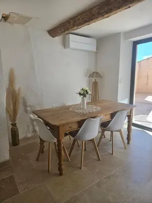 a dining room with a wooden table and white chairs at Maison de village chaleureuse in Sainte-Tulle