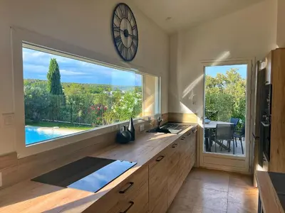 a kitchen with a large window and a clock on the wall at Le Moulin in Aix-en-Provence