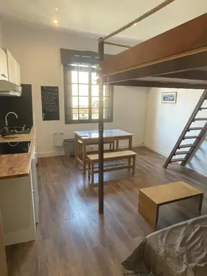 a living room with a loft bed and a table at Studio climatisé au centre du village in Saint-Michel-lʼObservatoire