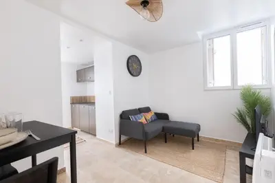 a living room with a chair and a clock on the wall at Suite Lueur de Sable - Hypercentre - WiFi in Apt