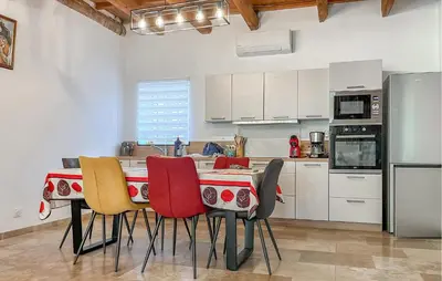 a kitchen with a table with colorful chairs in it at Proche Alpilles in Eyragues