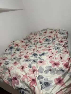 a bed with a floral comforter on it at Apparemment t3 in Noves