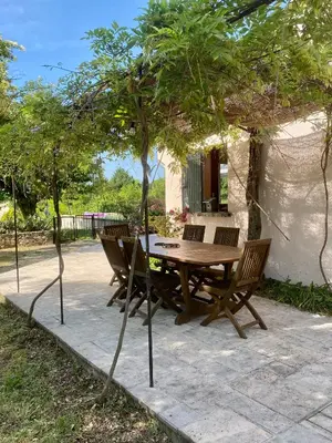 a wooden table and chairs under a tree at Le Pré de la Reyne in Sault-de-Vaucluse