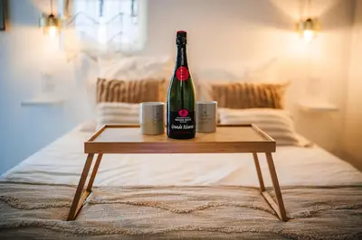 a bottle of wine sitting on a table on a bed at Évasion grecque en duo Suite balnéo Wifi in Carpentras