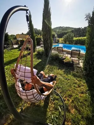 a man laying in a hammock by a pool at Petite maison avec piscine le chêne vert in Gargas