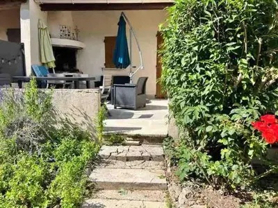 a garden with a patio with a table and umbrella at Au pied du Colorado Provencal in Rustrel