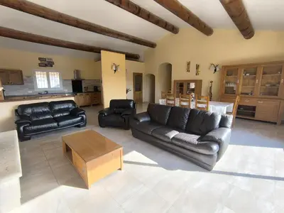 a living room with black leather couches and a table at La Colline sous les etoiles in Lincel