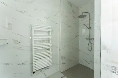 a bathroom with a shower with white marble walls at Villa le Trèfle with pool in Velaux