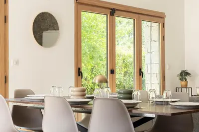 a dining room with a wooden table and white chairs at Villa le Trèfle with pool in Velaux