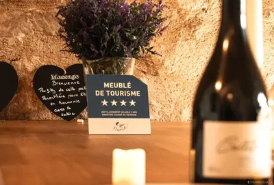 a bottle of wine and a vase with flowers at Domaine Paradis in Reillanne