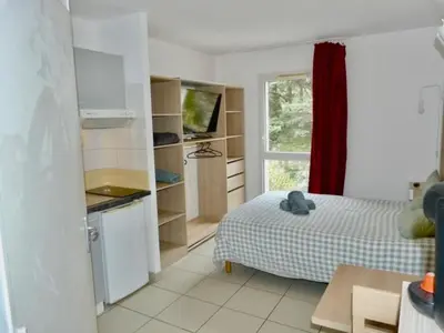 a bedroom with a bed and a kitchen with a window at Le Clos d'AIX Studio 113 in Aix-en-Provence