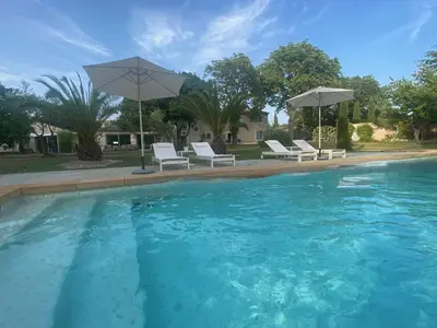 a swimming pool with white chairs and umbrellas at Mas de la Calade Bed & Breakfast in Aix-en-Provence