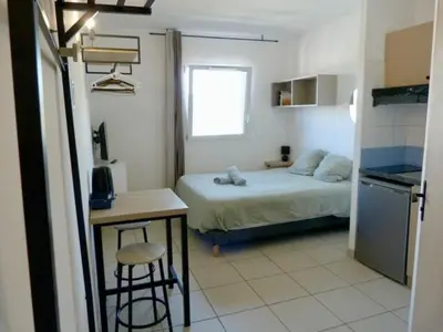 a bedroom with a bed and a table and a kitchen at Le Clos d'AIX Studio 304 Parking in Aix-en-Provence