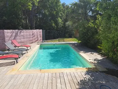 a swimming pool with two chairs on a wooden deck at Villa Eguilles, ensoleillée, piscine à 10 mn d' Aix en Provence in Éguilles