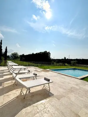 a row of benches next to a swimming pool at Maison Poumo, Piscine, clim & padel privé,12 pers in LʼIsle-sur-la-Sorgue