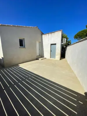 a white building with two doors and a driveway at Maison climatisée avec jardin in Caumont-sur-Durance