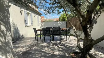 a patio with a table and chairs next to a building at Maison climatisée avec jardin in Caumont-sur-Durance
