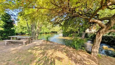 a picnic table sitting next to a river at Cosy & Cocooning in Le Thor