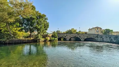 a bridge over a river with trees and water at Cosy & Cocooning in Le Thor