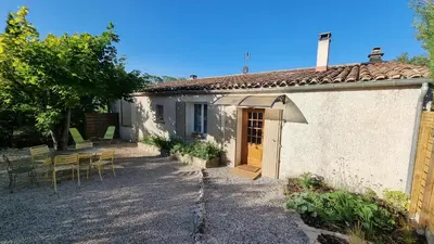 a small white house with a table and chairs at Gîte Le Verger Paisible in Malemort-du-Comtat