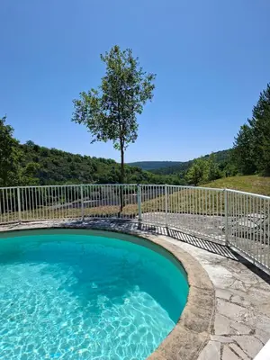 a swimming pool with a fence and a tree at Cabanon provençal en pierre entouré de lavandes in Vachères