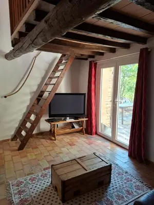 a living room with a flat screen tv and a staircase at Cabanon provençal en pierre entouré de lavandes in Vachères