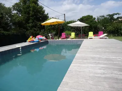 a swimming pool with chairs and an umbrella at La bergerie in Cadenet