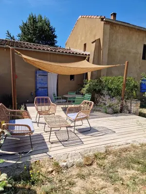a patio with chairs and a table and a umbrella at Le colibri du Luberon in Apt