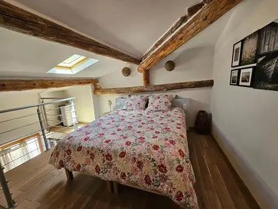 a bedroom with a bed with a red comforter at Le nid douillet in Pertuis