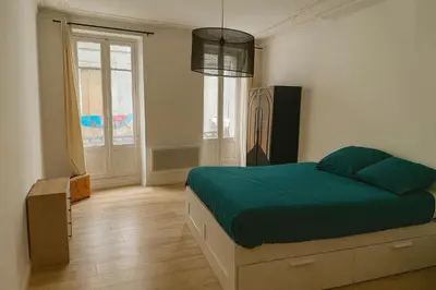 a bedroom with a bed with green sheets and a window at Bel appartement 1er étage au centre ville de Carpentras in Carpentras