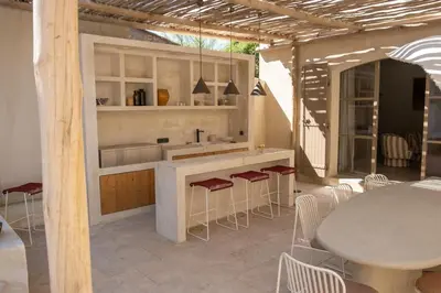 a kitchen with a counter and chairs and a table at Villa entièrement rénovée in Saint-Rémy-de-Provence