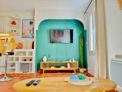 a living room with a table and a tv on a wall at Refuge reposant - Centre ville - Espace Bureau in Aix-en-Provence