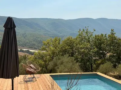 an umbrella and chairs next to a swimming pool at Bastidon avec vue et piscine au coeur du Luberon in Céreste