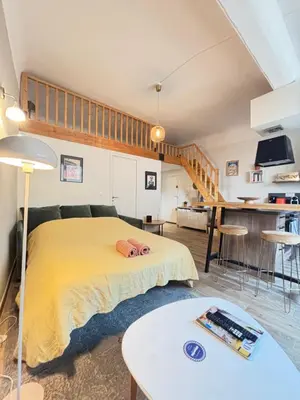 a bedroom with a yellow bed and a kitchen at Studio charmant centre historique au calme in Aix-en-Provence