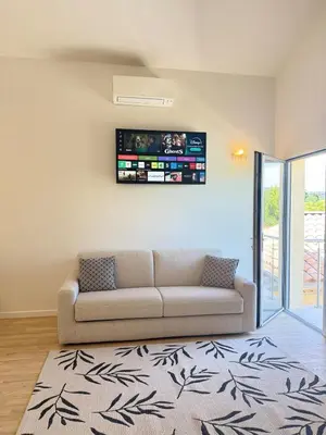 a living room with a couch and a tv on the wall at Le Quatre Relax in Aix-en-Provence