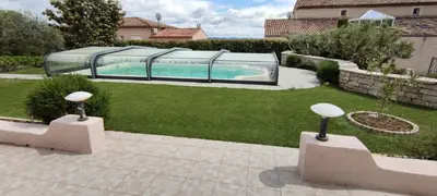 a swimming pool with a glass enclosure in a yard at le Jardin de Flore in Manosque