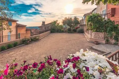a courtyard with pink and white flowers and buildings at Studio cosy proche d Aix en Provence climatisé in Éguilles