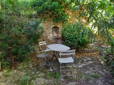 a table and chairs sitting next to a stone wall at Il était une fois à Lagnes in Lagnes
