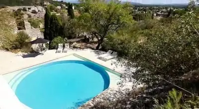 a large blue swimming pool in a field with trees at Le Fort de Bramafan in Caumont-sur-Durance