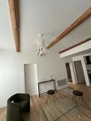 a living room with a couch and a kitchen at CARPENTRAS appartement 3e étage situé dans le centre historique in Carpentras