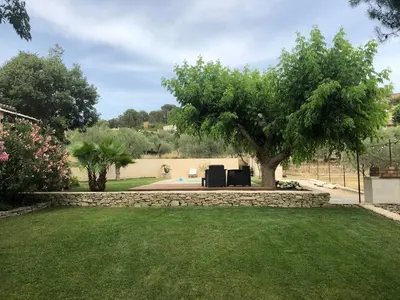 a garden with a tree and a stone wall at Gîte ,studio dans le village de lagnes in Lagnes